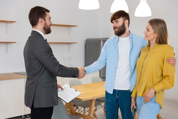 Male real estate agent doing business and showing house to potential buying couple