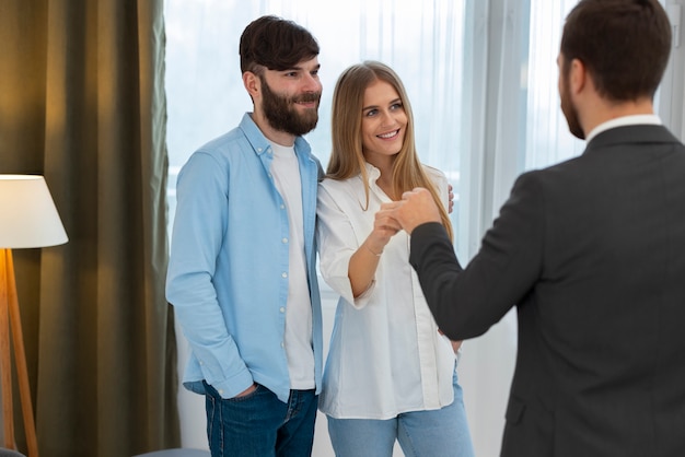 Male real estate agent doing business and showing house to potential buying couple