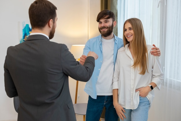 Free photo male real estate agent doing business and showing house to potential buying couple