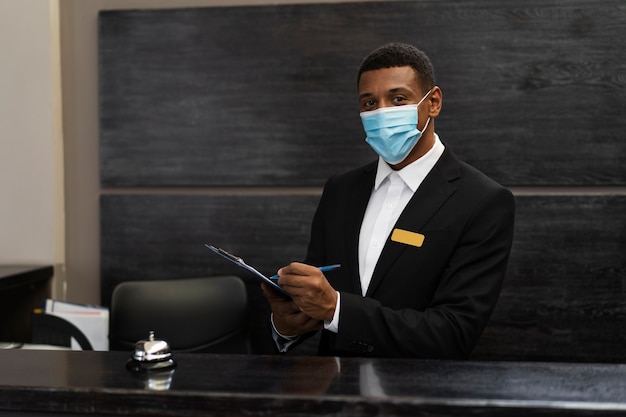 Секретарь-мужчина в костюме на работе в медицинской маске