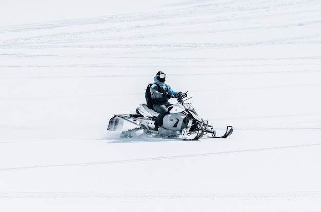 Foto gratuita maschio in sella a una motoslitta in un grande campo nevoso