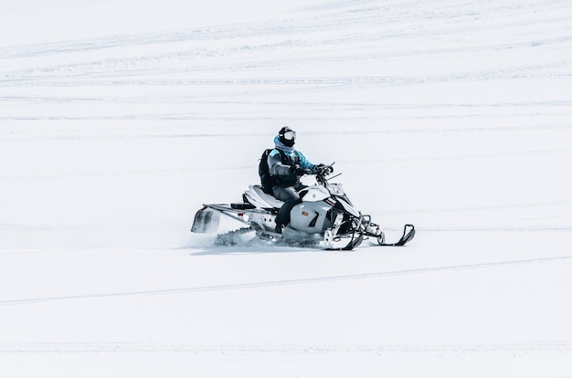 大きな雪原でスノーモービルに乗る男性