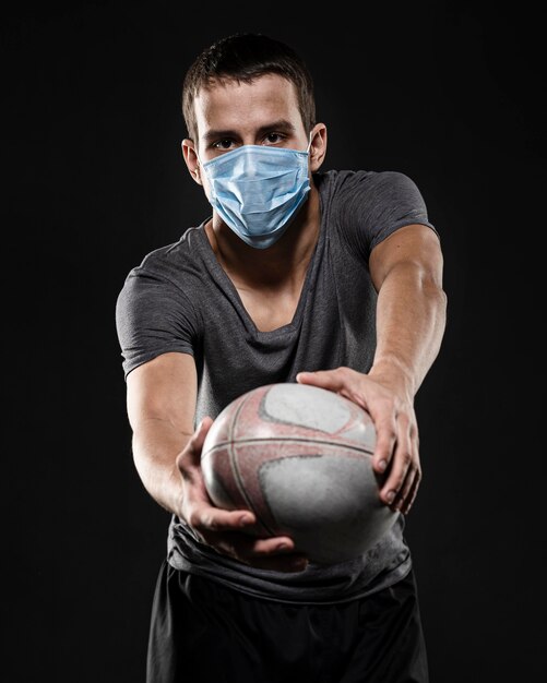 Male rugby player with medical mask holding ball