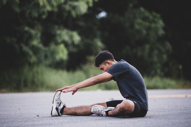 Foto gratuita corridore maschio facendo esercizio di stretching, preparando per allenamento