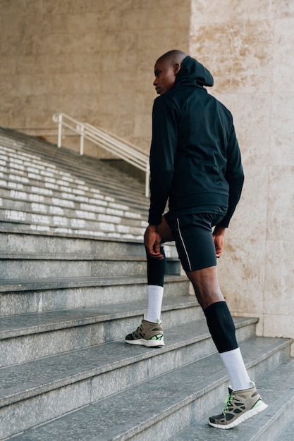 Free photo a male runner in hoodie top walking on staircase