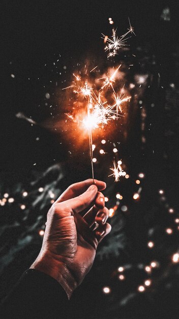 Male's hand holding a sparkling stick with a dark background