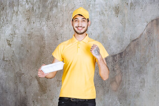 Male service agent in yellow uniform holding a white takeaway box and showing his fist.