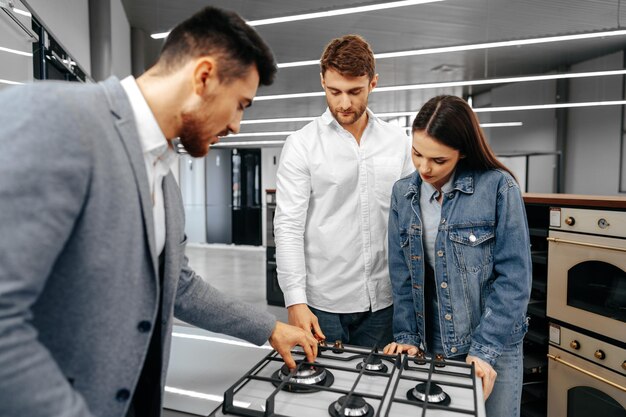 Free photo male shop assistant helps young couple to choose new home appliance