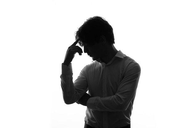 Male silhouette in thinking pose posing side view shadow back lit white background young