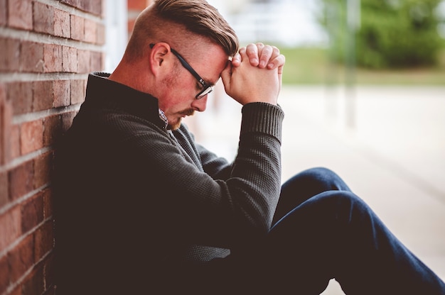 Male sitting near the wall while praying