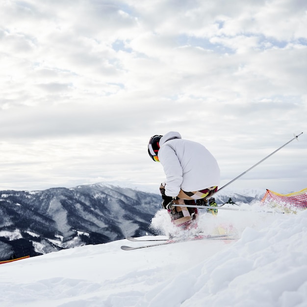 山の深い雪の下り坂の谷をスキーする男性スキーヤー