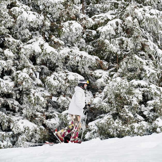 Male skier walking through snow in winter forest