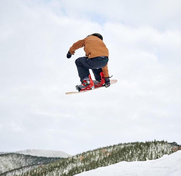 Male snowboarder doing tricks in the air at ski resort