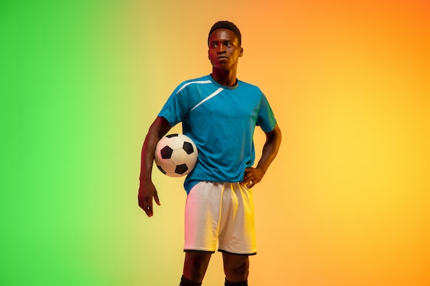 Free photo male soccer, football player training in action isolated on gradient studio in neon light