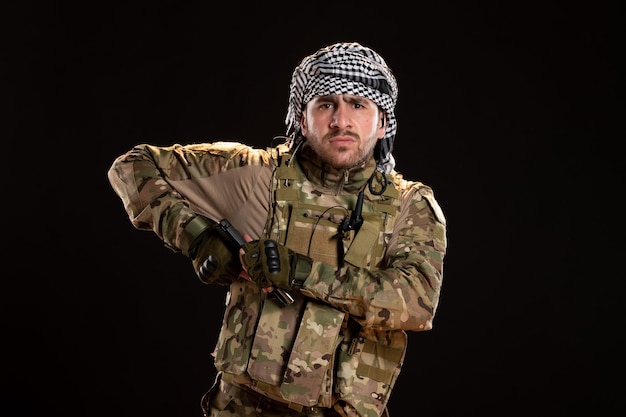 Male soldier in camouflage fighting with gun on black wall