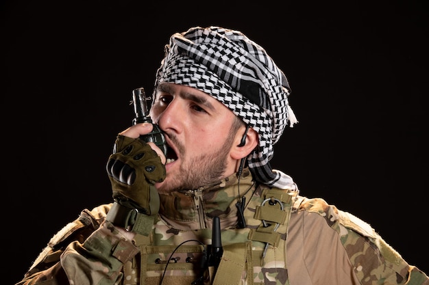 Male soldier in camouflage holding grenade on a black wall