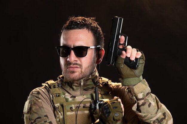 Male soldier in camouflage with gun on black wall