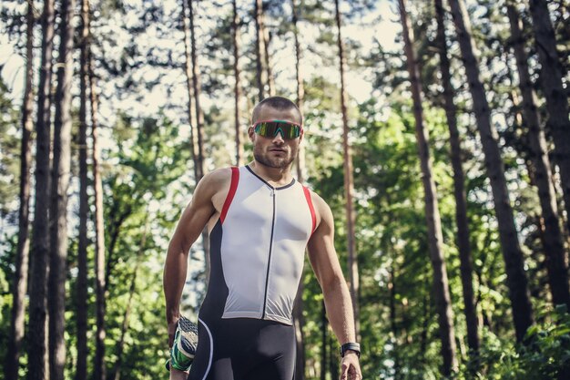 森の中を走るスポーツウェアとサングラスの男性。
