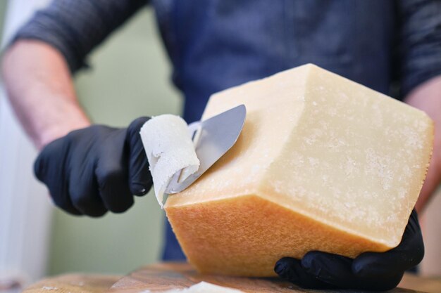 Мужской персонал нарезает блок сыра в местном супермаркете