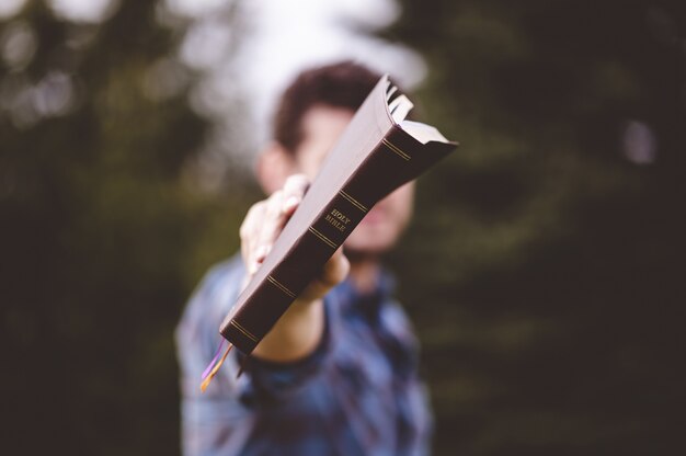 male standing and holding a book in hands