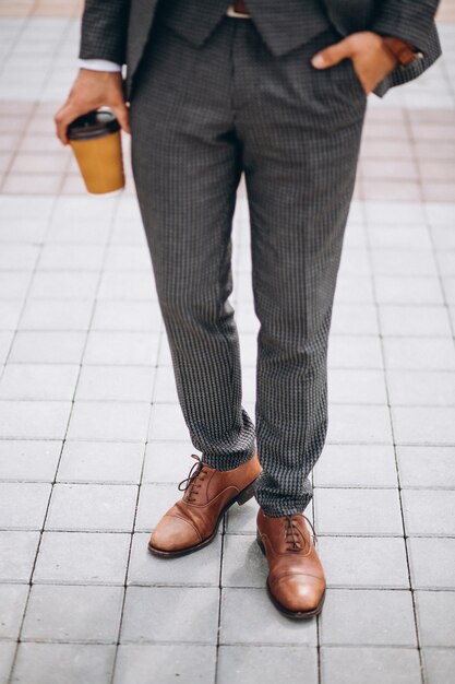 男性のスーツは、手にコーヒーを保持することを閉じます