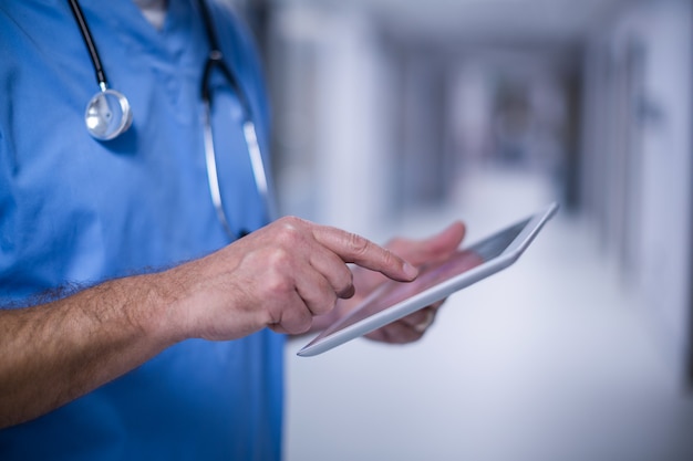 male surgeon using digital tablet in operation room