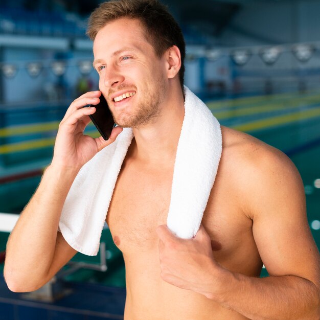 電話で話しているプールで男性スイマー