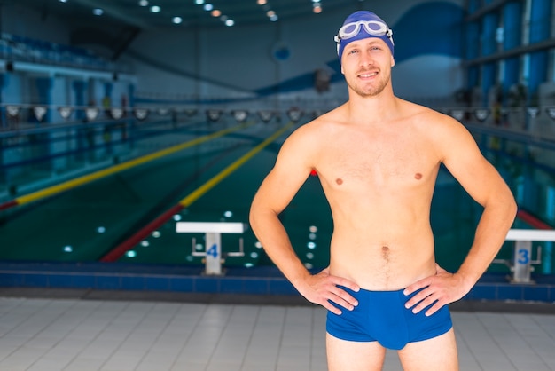 Foto gratuita nuotatore maschio che posa davanti alla piscina