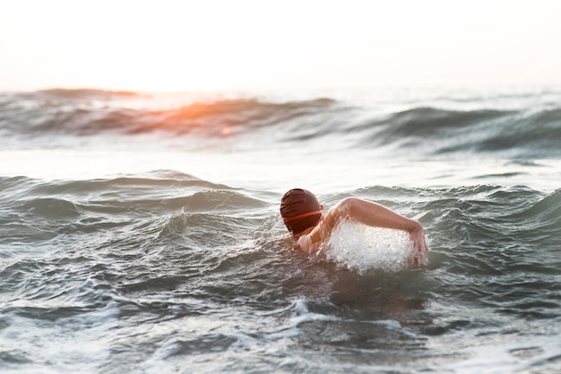 Foto gratuita nuotatore maschio che nuota nell'oceano