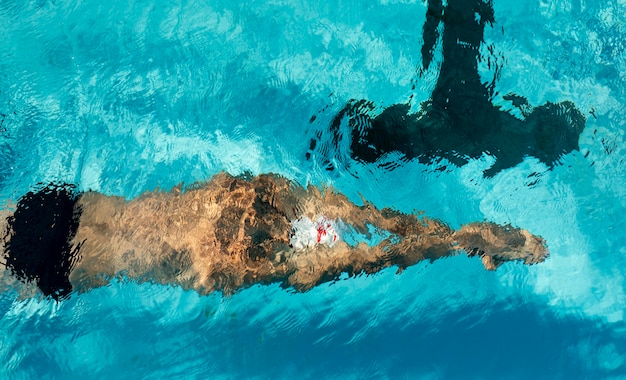 Foto gratuita nuotatore maschio che nuota nella piscina di acqua