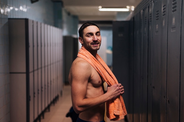 Free photo male swimmer with towel in locker room