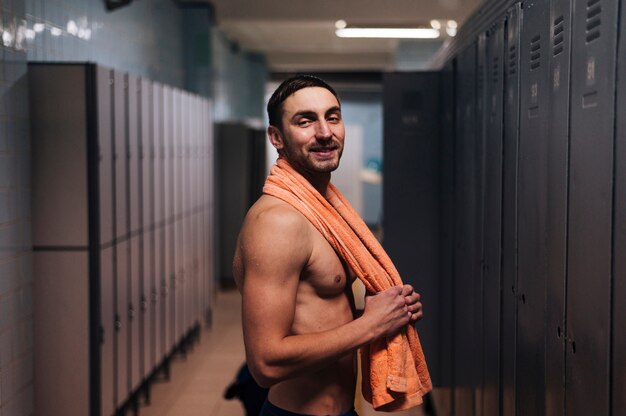 Male swimmer with towel in locker room