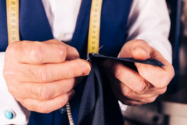 Free photo a male tailor's hand sewing the fabric with needle