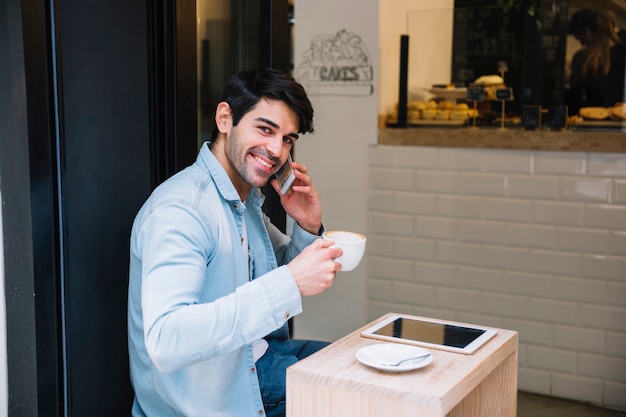 Male talking on smartphone sitting in cafe