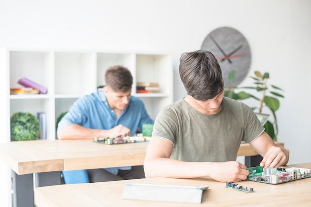 Studenti maschii che riparano la scheda madre nel centro di servizio