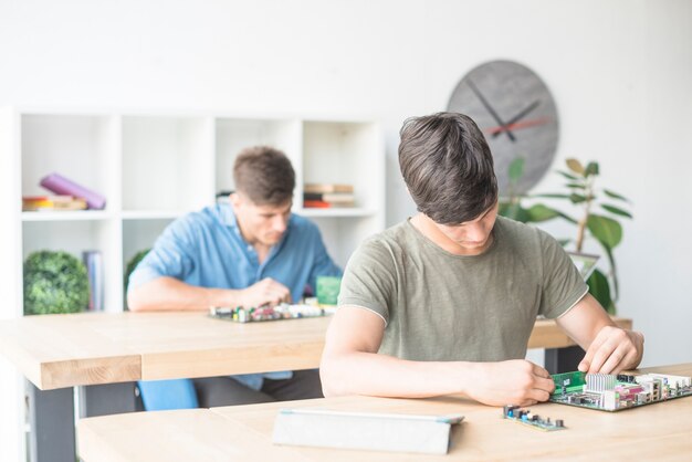 Male technician students repairing motherboard in service center