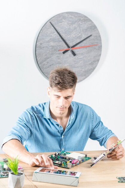 Male technician using digital tablet while repairing motherboard