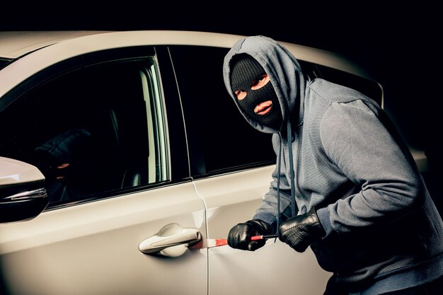 남자 도둑은 지렛대로 차 문을 열 것입니다.