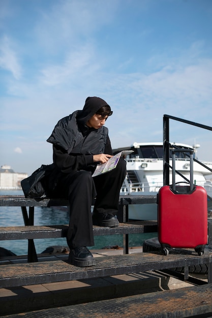 Male tourist checking map next to suitcase