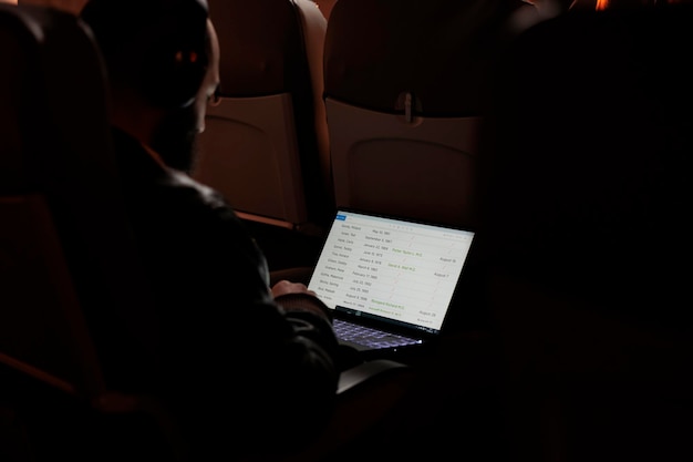 Free photo male tourist flying with airplane and using laptop to browse on internet website during sunset flight. man travelling in economy class to arrive at holiday destination, aerial transport.