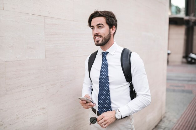 Male tourist standing near wall with his cellphone