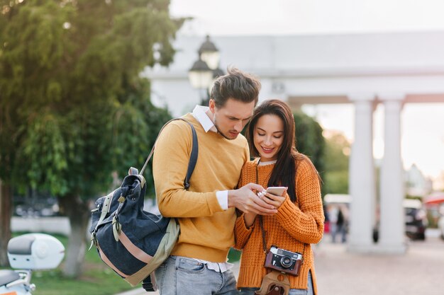 Male tourist with backpack looking at phone screen with serious face expression