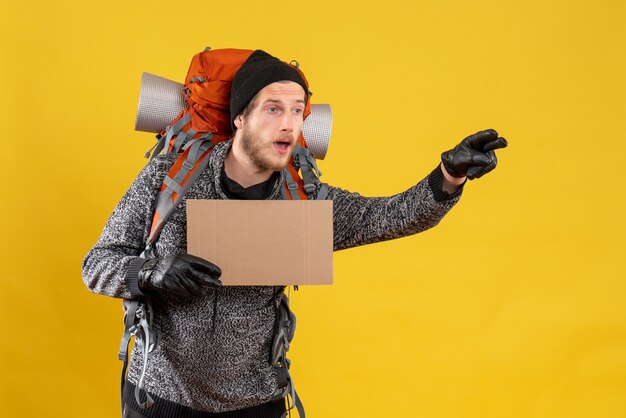 male tourist with leather gloves and backpack holding blank cardboard hitchhiking