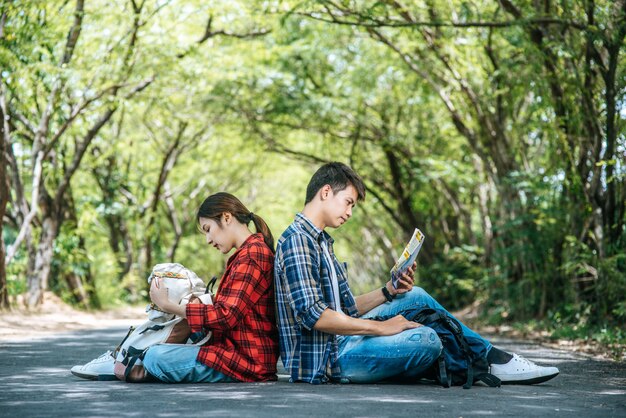 男性の観光客が地図を見る女性の観光客は荷物を見て、寄りかかっています。