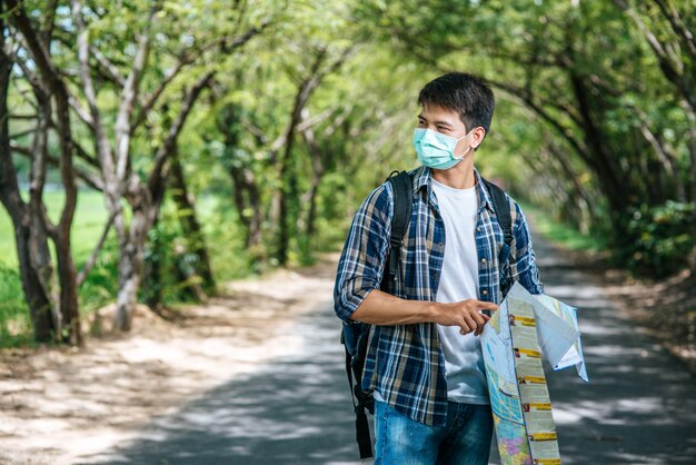 男性の観光客が立ち、道路上の地図を見てください。