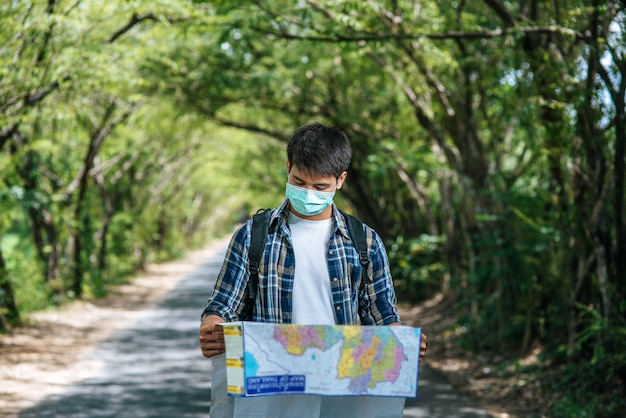 I turisti maschi stanno e guardano la mappa sulla strada.