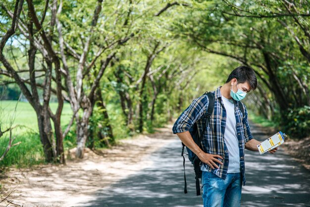 男性の観光客が立ち、道路上の地図を見てください。