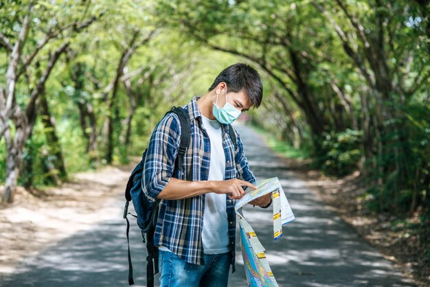 Male tourists stand and look at the map on the road.