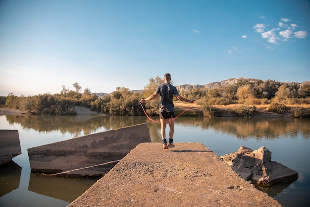 Male training with a jumping-rope next to the river