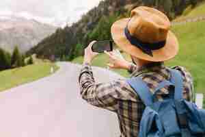 Foto gratuita viaggiatore maschio in cappello marrone che cerca la strada giusta usando la mappa in linea che sta sulla bella montagna